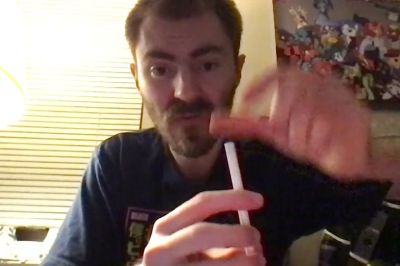 Bearded man plays a traditional string instrument under warm light in anime-filled room - yesvids.com