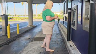 Woman in green and hijab meets stranger by silver SUV in parking lot - yesvids.com
