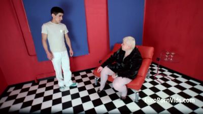 Mature woman in pantyhose dominates multiple naked men in a vibrant studio - yesvids.com