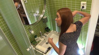 Blonde woman adjusts her hair in front of the bathroom mirror wearing a black floral dress - yesvids.com - Usa